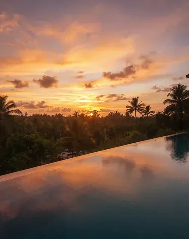 A vivid sunset sky over the pool and forest horizon